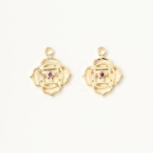 May include: Two gold-colored metal charms in the shape of a mandala with a red gemstone in the center.