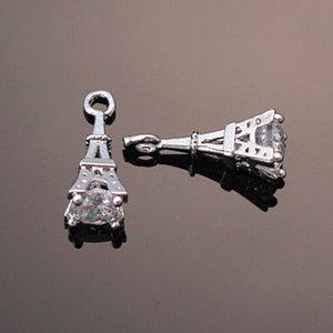 May include: Two silver Eiffel Tower charms with clear rhinestone accents. The charms have a loop at the top for attaching to jewelry.