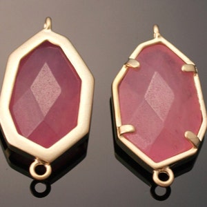 May include: Two gold-toned pendant charms with a faceted pink glass stone in the center. Each charm has a loop at the top and bottom for attaching to jewelry.