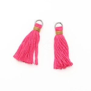 May include: Two pink yarn tassels with gold trim and silver rings.