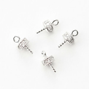 Puede incluir: Cuatro tapas de cuentas plateadas con un diseño de alambre retorcido y un adorno de cristal transparente.