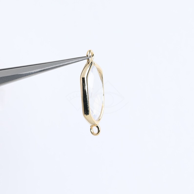 May include: Gold-toned metal pendant with a clear glass octagon-shaped bezel. The pendant has a loop at the top and a jump ring at the bottom.