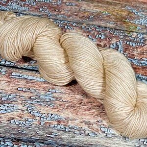 May include: A skein of beige yarn, made of soft, natural fibers, perfect for knitting or crocheting.