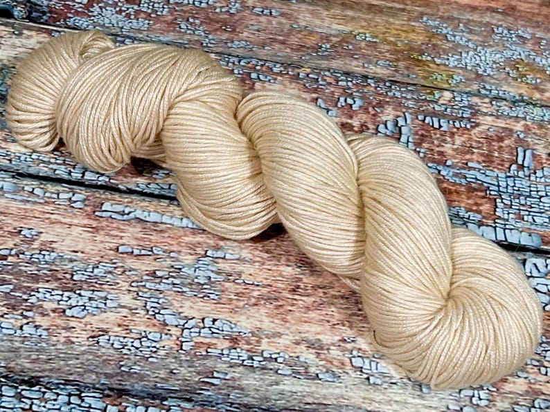 May include: A skein of beige yarn, made of soft, natural fibers, perfect for knitting or crocheting.