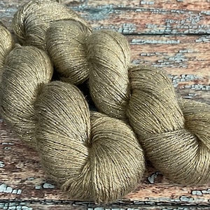 May include: A skein of gold yarn with a subtle shimmer. The yarn is soft and fluffy, and it would be perfect for knitting or crocheting a cozy scarf or sweater.