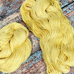 May include: Two skeins of yellow yarn, one skein is in a loose ball and the other is in a long strand.