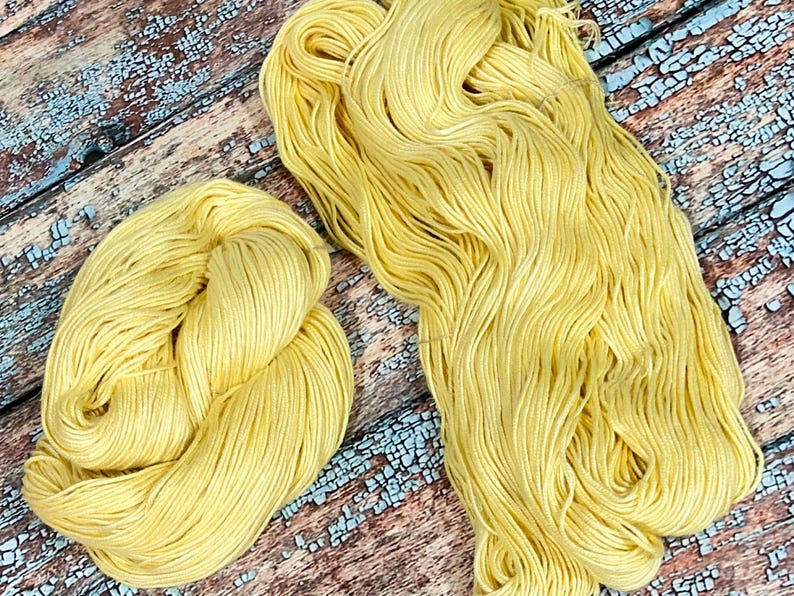 May include: Two skeins of yellow yarn, one skein is in a loose ball and the other is in a long strand.