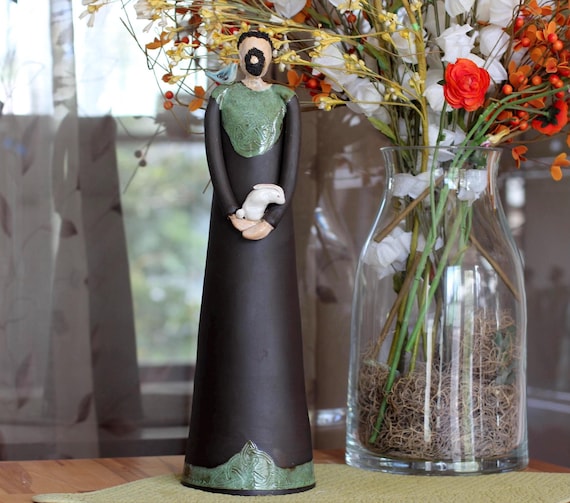 A hand-built ceramic St. Francis sculpture with intricate Celtic knotwork, a bird, and a bunny — the kind of deeply personal religious folk art you'd find in a monastery gift shop and never forget.