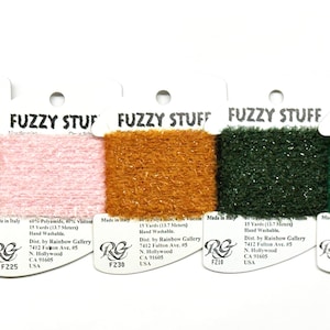 May include: Five spools of Fuzzy Stuff yarn in various colors: dark green, light pink, golden brown, forest green, and emerald green. Each spool is labeled with the brand and product information. The yarn is 15 yards (13.7 meters) and hand washable.