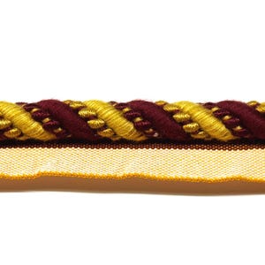 May include: Close-up of decorative trim featuring a twisted rope design. The trim has a burgundy and gold rope pattern with a cream-colored fabric base. The trim is likely used for upholstery or decorative purposes.