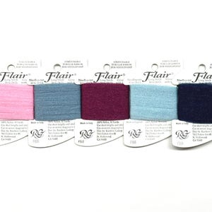 May include: Five spools of Flair brand stretchable tubular ribbon for needlepoint in various colors: pink, blue, burgundy, light blue, and navy. Each spool contains 10 yards of 100% nylon ribbon. The packaging includes the brand name and product information.
