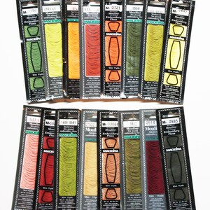 May include: A collection of 16 spools of Madeira Mouline embroidery floss in various colors. Each spool is labeled with the brand name, the color number, and the length of the floss in yards. The floss is made of six strands of 100% cotton.