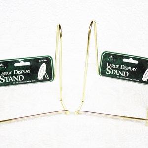 May include: Two gold metal display stands for large items. Each stand is labeled "Large Display Stand" with the product number "23-1284".