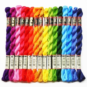 May include: A collection of 15 spools of DMC embroidery floss in a rainbow of colors, including purple, pink, red, orange, yellow, green, blue, and navy. Each spool is labeled with the DMC color number.