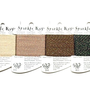 May include: Four spools of Sparkle Ray needlepoint thread in various colors: beige, rose gold, brown, and dark green. Each spool is labeled with the brand name and product details. The thread is 9 yards (8.2 meters) long.