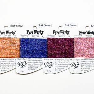 May include: A collection of six spools of Fyre Werks Soft Sheen thread in various colors, including gold, orange, blue, burgundy, pink, and purple. Each spool is labeled with the brand name and product details.