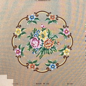 May include: A beige needlepoint canvas with a floral design. The design features a bouquet of pink, yellow, and white flowers with green leaves, surrounded by a brown, ornate frame. The canvas is labeled "60x60" and "Made in EU" in the bottom left corner.