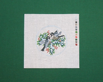 May include: A white canvas with a design of two birds perched on a branch with red berries. The design is in shades of green, blue, red, and white.