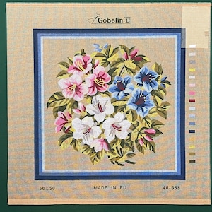May include: A beige needlepoint canvas with a floral design featuring pink, white, and blue flowers. The canvas is labeled "Gobelin" and "Made in EU".