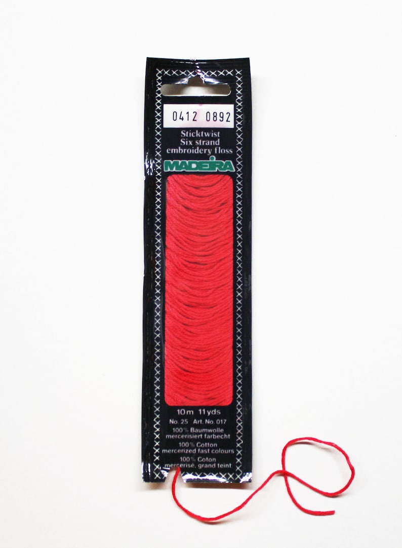 May include: A package of red Madeira Sticktwist six-strand embroidery floss. The black label displays the product information, including the length of 11 yards. A strand of the red floss is loose.