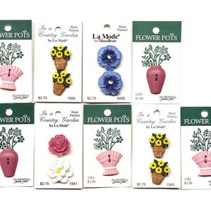 May include: A collection of hand-painted flower-themed buttons on green and white cards. Designs include sunflowers in pots, blue pansies, pink vases, and a pink flower basket. The cards have the text "Flower Pots" and "In a Country Garden".