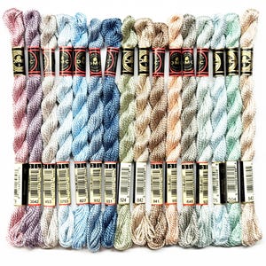 May include: A collection of 15 DMC embroidery floss spools in various shades of blue, green, pink, and beige. The spools are labeled with DMC numbers, including 3042, 453, 3753, 827, 932, 931, 524, 842, 841, 958, 648, 921, 75, 504, and 543.
