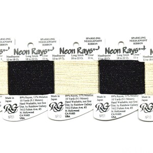 May include: Five spools of Neon Rays sparkling needlepoint ribbon arranged in a row. The spools alternate between a metallic gold and a solid black color. Each spool features printed text including Neon Rays, 10 Yards, and Made in Japan.