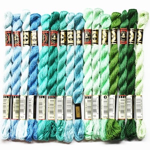 May include: A collection of 15 DMC embroidery floss spools in shades of blue, green, and teal. The spools are arranged in a row and labeled with their corresponding DMC numbers.