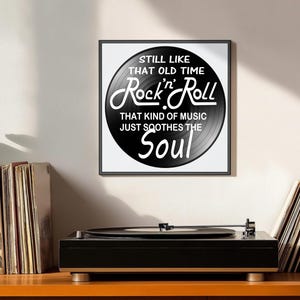 K&ouml;nnte beinhalten: Ein gerahmter Druck mit einem schwarzen Vinyl-Schallplatten-Design, das den Text "STILL LIKE THAT OLD TIME Rock 'n' Roll THAT KIND OF MUSIC JUST SOOTHES THE Soul" in Wei&szlig; zeigt. Ein schwarzer Plattenspieler befindet sich darunter.