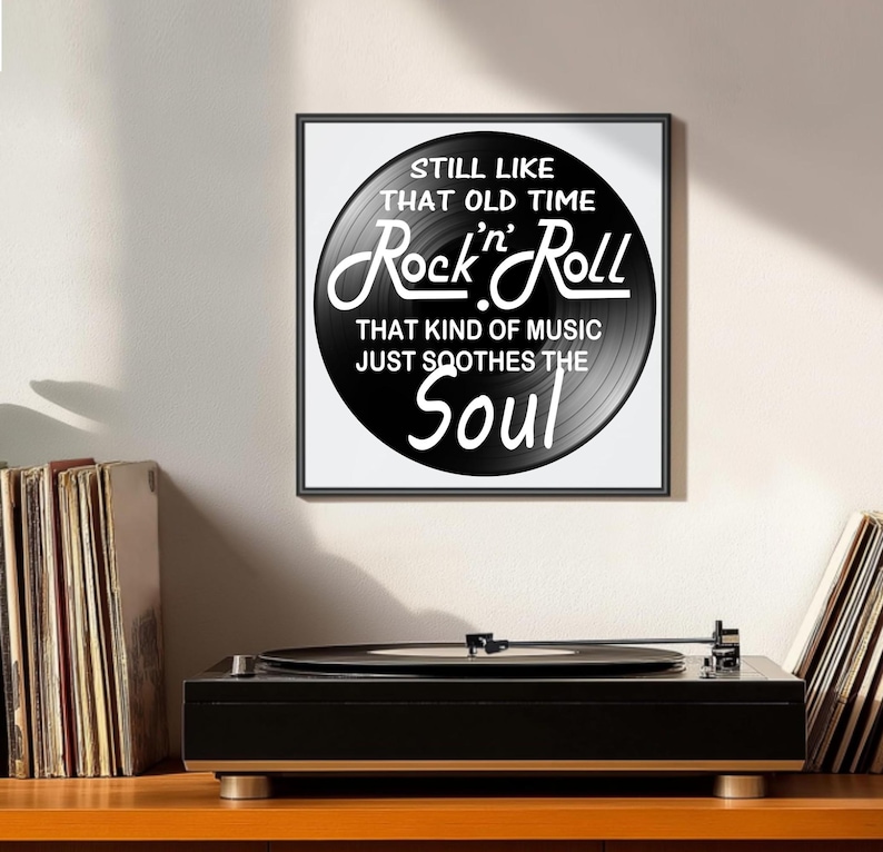 K&ouml;nnte beinhalten: Ein gerahmter Druck mit einem schwarzen Vinyl-Schallplatten-Design, das den Text "STILL LIKE THAT OLD TIME Rock 'n' Roll THAT KIND OF MUSIC JUST SOOTHES THE Soul" in Wei&szlig; zeigt. Ein schwarzer Plattenspieler befindet sich darunter.