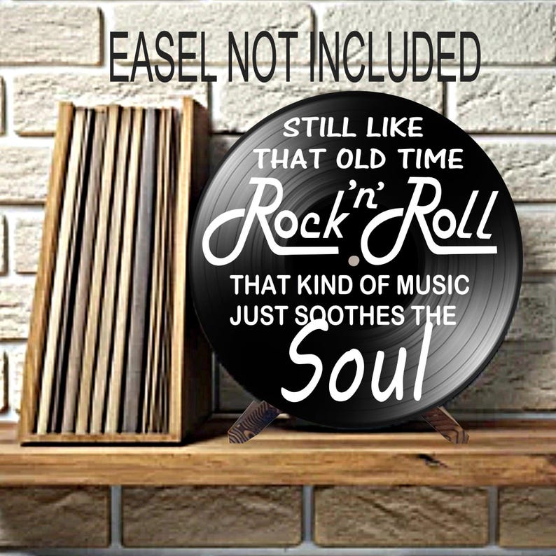 K&ouml;nnte beinhalten: Eine schwarze Schallplatte mit wei&szlig;em Text, der lautet: "Still Like That Old Time Rock 'n' Roll That Kind of Music Just Soothes the Soul". Die Platte wird auf einem Holzst&auml;nder pr&auml;sentiert.