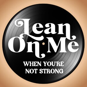 May include: A black vinyl record with the words "Lean On Me" in white, stylized lettering. Below, the text reads "When You're Not Strong". The record is set against a tan background.