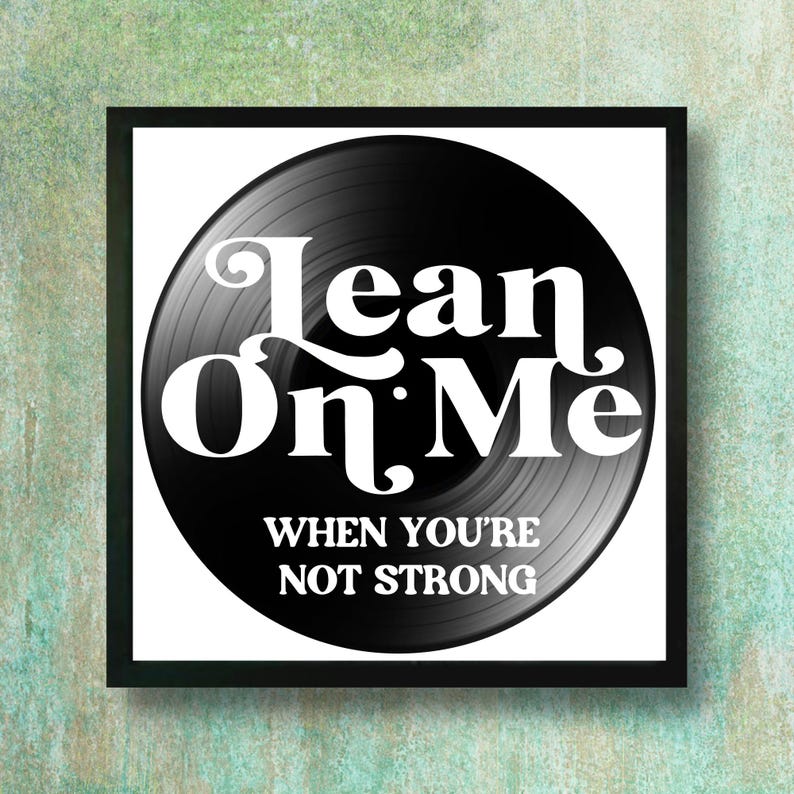 A Vinyl Record in a black metal frame. The record has white text that reads 'Lean On Me When You're Not Strong.'