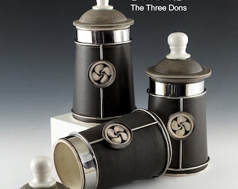 Jars. Price Each. Only 2 left! Porcelain with stainless steel and a basque medalion of good fortune. 9" high