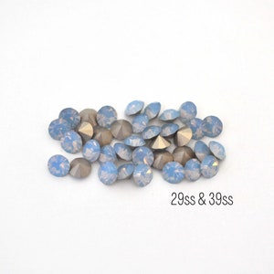 May include: A pile of light blue iridescent rhinestones with silver settings. 29ss & 39ss.