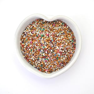 May include: A heart-shaped bowl filled with a variety of colorful and metallic rhinestones. The rhinestones are small and sparkly, and they are perfect for crafting or decorating.