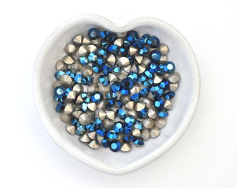 May include: A heart-shaped dish filled with blue and silver rhinestones. The rhinestones are small and have a faceted design.