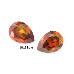 May include: Two pear-shaped gemstones, each measuring 18x13mm, with a deep orange colour and a faceted cut.