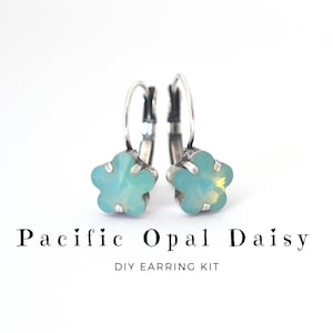 May include: A pair of daisy-shaped earrings with a Pacific Opal design. The earrings feature a light blue and yellow crystal flower set in a silver-colored metal. The text "Pacific Opal Daisy DIY Earring Kit" is displayed below the earrings.