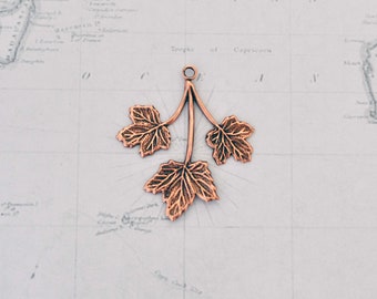 May include: A copper-colored pendant featuring a three-leaf branch with detailed leaf veins. The pendant is perfect for adding a touch of nature to jewelry projects.