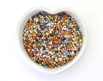 May include: A heart-shaped bowl filled with a variety of colorful rhinestones, including gold, silver, blue, red, and green.