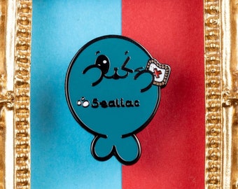 Könnte beinhalten: Eine blaue und weiße Emaille-Anstecknadel mit einer Comicfigur mit dem Text "Sealiao" in einem verzierten goldenen Rahmen.