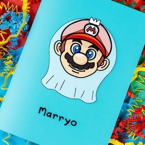Marryo - Mario Engagement Wedding Card on red, blue & green card with crinkle card confetti. Blue a6 congratulations card of a smiling nintendo mario character head wearing a white bridal wedding veil, underneath him is black text reading Marryo.