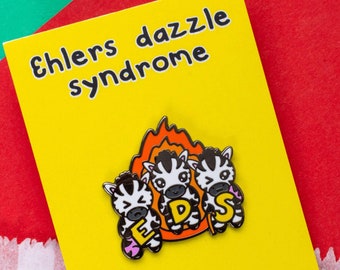 May include: Yellow card with the text "Ehlers dazzle syndrome" and a cartoon image of three zebras with the letters "EDS" on them. The zebras are on fire. The card also has the website "www.innabox.co.uk" and the text "Follow me on social media!" with links to Facebook, Twitter, and Instagram.