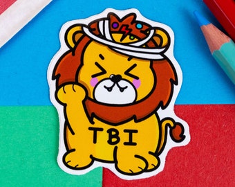 Può includere: Un leone di cartone animato giallo con una benda sulla testa e il testo "TBI" sul petto. Il leone indossa una benda sulla testa e ha un'espressione carina sul viso.