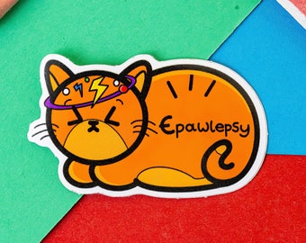 Può includere: Sticker di gatto arancione cartone animato con una fascia viola e bianca, un fulmine e punti rossi e verdi. Il gatto è sdraiato con la coda arrotolata attorno al suo corpo. Il testo "Epawlepsy" è scritto sullo sticker.