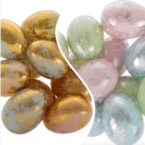 May include: A collection of iridescent Easter eggs in gold, pink, and blue colors. The eggs have a speckled, textured finish.