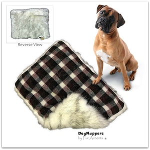 May include: A plaid dog bed with a white faux fur trim. The bed is made by DogNappers by Fur Accents. A brown and white boxer dog is sitting next to the bed.