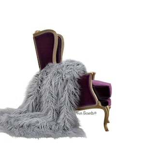 Puede incluir: Una manta de piel sintética gris y suave drapeada sobre un sillón de terciopelo morado con patas ornamentadas pintadas de oro. El sillón tiene un respaldo alto y un marco curvo y adornado. El texto "Fur Accents®" es visible en el sillón.