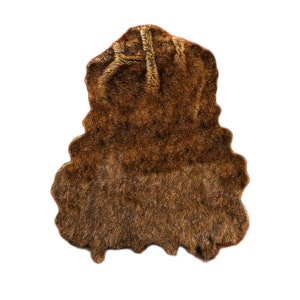 May include: A brown faux fur rug with a shaggy texture. The rug is shaped like a hide and has a natural, organic look.